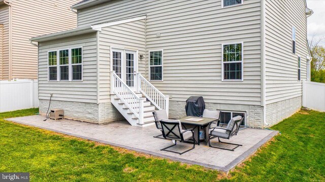 rear view of house with fence, a yard, and a patio area