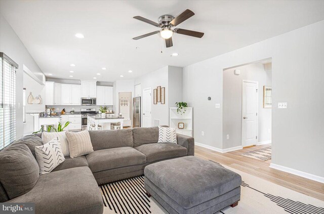 living area featuring recessed lighting, baseboards, ceiling fan, and light wood-type flooring
