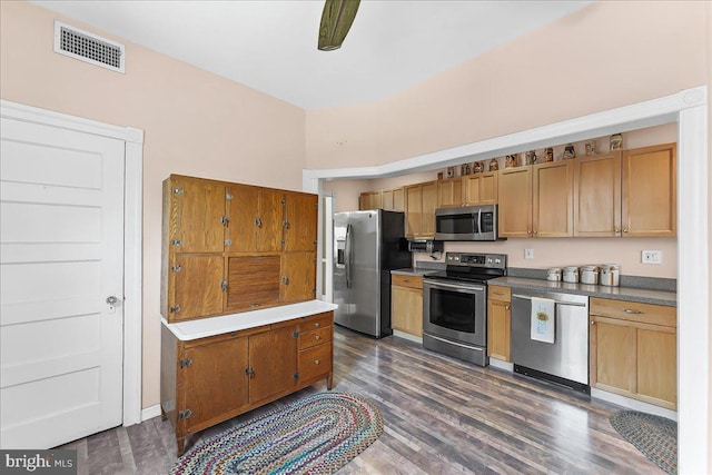 kitchen featuring brown cabinetry, stainless steel appliances, dark wood-type flooring, and visible vents