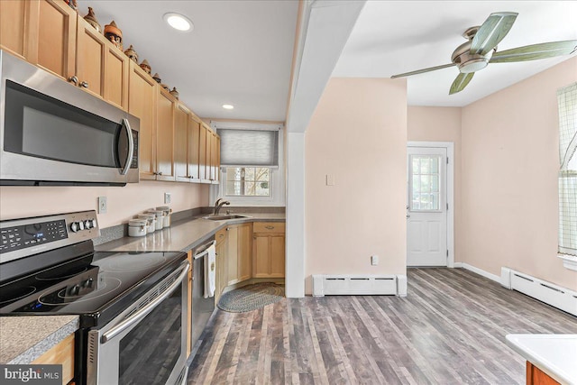 kitchen featuring a baseboard heating unit, appliances with stainless steel finishes, a wealth of natural light, and a sink