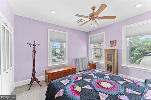 bedroom featuring radiator heating unit, baseboards, multiple windows, and visible vents