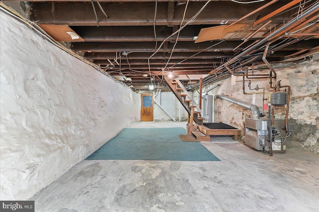 unfinished basement featuring a heating unit, water heater, and stairway