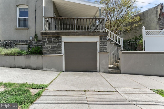 exterior space with fence, a garage, stucco siding, concrete driveway, and a balcony