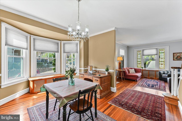 dining area with a notable chandelier, ornamental molding, a wealth of natural light, and light wood finished floors
