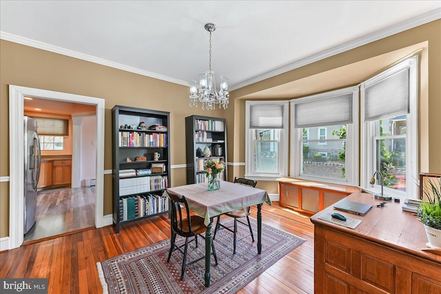 dining space featuring ornamental molding, a baseboard radiator, a notable chandelier, and hardwood / wood-style flooring