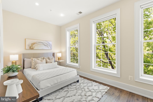 bedroom with baseboards, visible vents, multiple windows, and hardwood / wood-style flooring