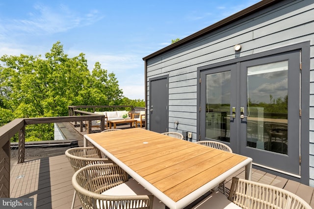 wooden terrace with outdoor dining area, french doors, and an outdoor hangout area