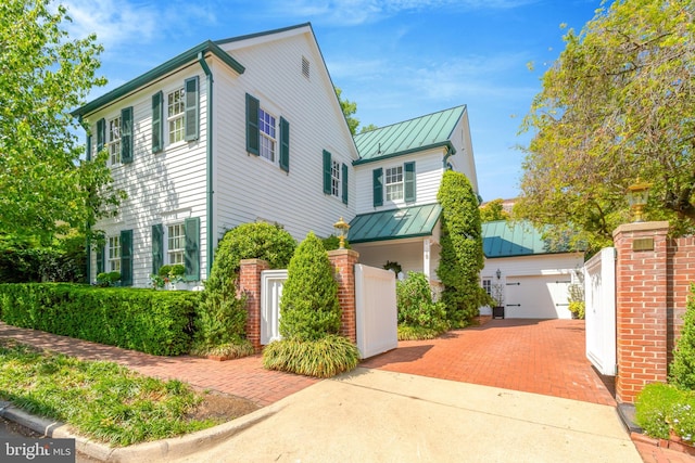 view of front facade featuring fence private yard, a garage, decorative driveway, a standing seam roof, and metal roof