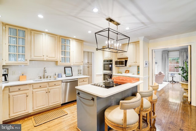 kitchen featuring a kitchen island, a kitchen bar, light countertops, a sink, and stainless steel appliances