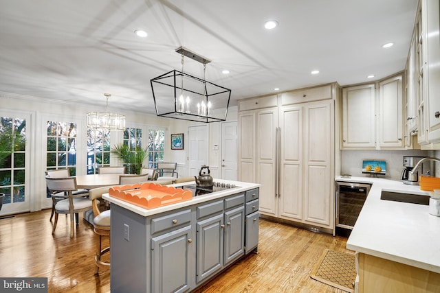 kitchen with a sink, light countertops, gray cabinets, a center island, and wine cooler