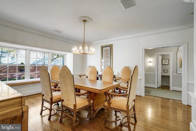 dining room featuring crown molding, light wood-style flooring, a chandelier, and visible vents