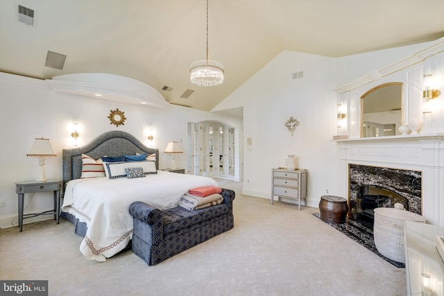 carpeted bedroom with visible vents, a notable chandelier, vaulted ceiling, and a fireplace