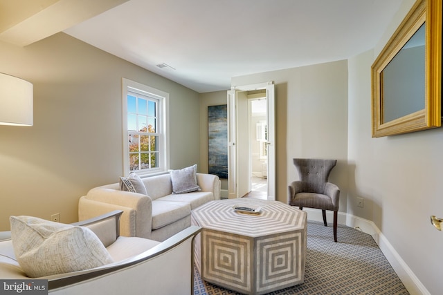 living room featuring visible vents, carpet, and baseboards