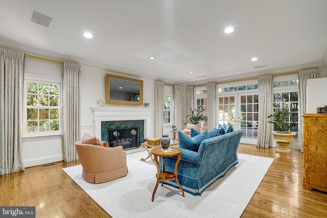 living room featuring a healthy amount of sunlight, french doors, visible vents, a fireplace, and ornamental molding