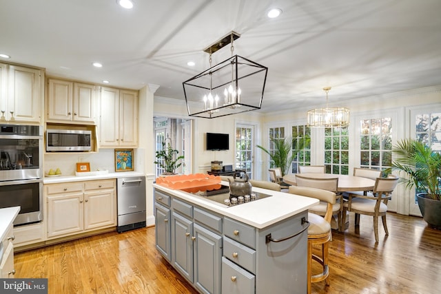 kitchen with light countertops, appliances with stainless steel finishes, gray cabinets, and a center island