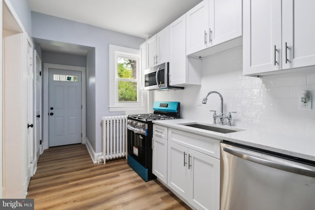 216 Homewood Ter, Baltimore, MD 21218 - kitchen featuring appliances with stainless steel finishes, radiator, a sink, white cabinets, and tasteful backsplash
