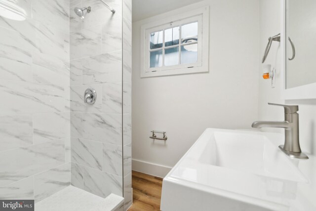 216 Homewood Ter, Baltimore, MD 21218 - bathroom featuring a tile shower, a sink, wood finished floors, and baseboards
