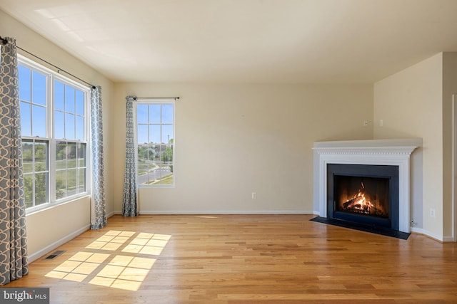 unfurnished living room featuring a fireplace with flush hearth, light wood-type flooring, and visible vents
