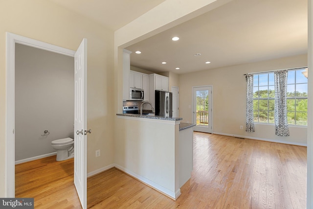 kitchen featuring white cabinetry, baseboards, appliances with stainless steel finishes, and light wood finished floors