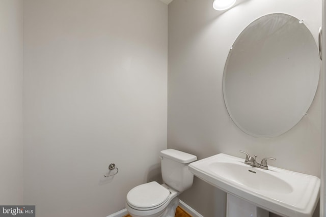 bathroom featuring baseboards, a sink, and toilet