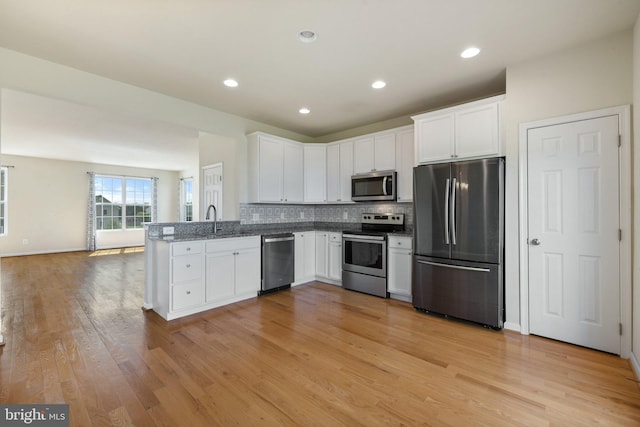 kitchen with decorative backsplash, light wood-style flooring, stainless steel appliances, and white cabinetry
