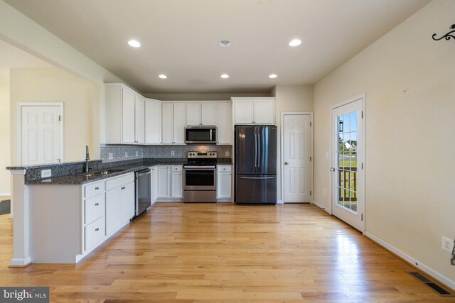 kitchen featuring visible vents, tasteful backsplash, white cabinets, stainless steel appliances, and light wood-style flooring