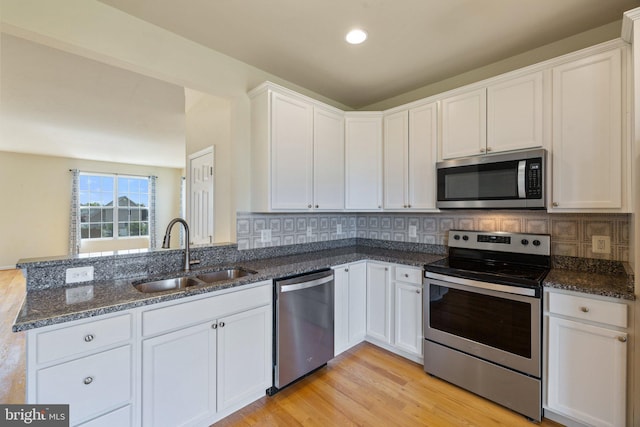 kitchen with a sink, appliances with stainless steel finishes, white cabinets, and light wood-style flooring