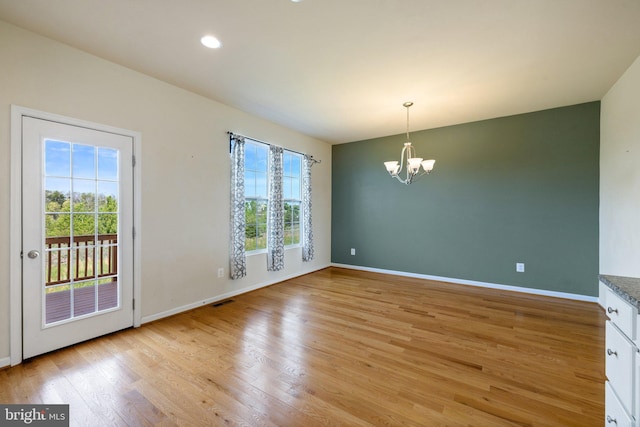 unfurnished dining area featuring baseboards, a chandelier, visible vents, and light wood-type flooring