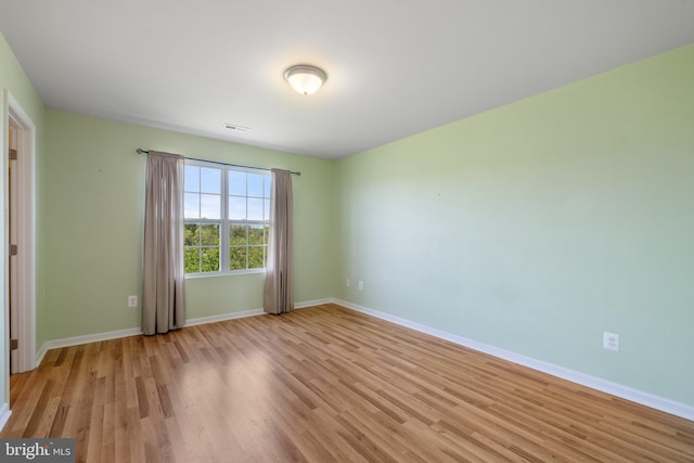 unfurnished room with baseboards, light wood finished floors, and visible vents