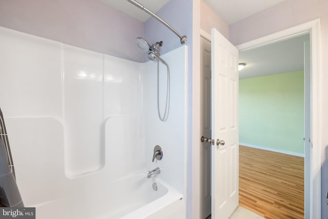 bathroom with shower / bath combination, baseboards, and wood finished floors