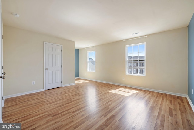 spare room featuring baseboards, light wood-type flooring, and visible vents