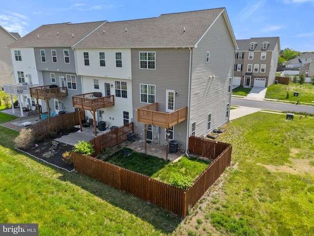 rear view of property featuring a fenced backyard, central AC, a yard, and a residential view