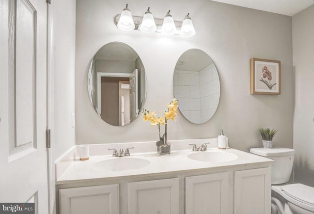 bathroom with a sink, toilet, and double vanity