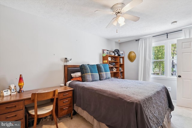 bedroom featuring a ceiling fan, a textured ceiling, and light carpet