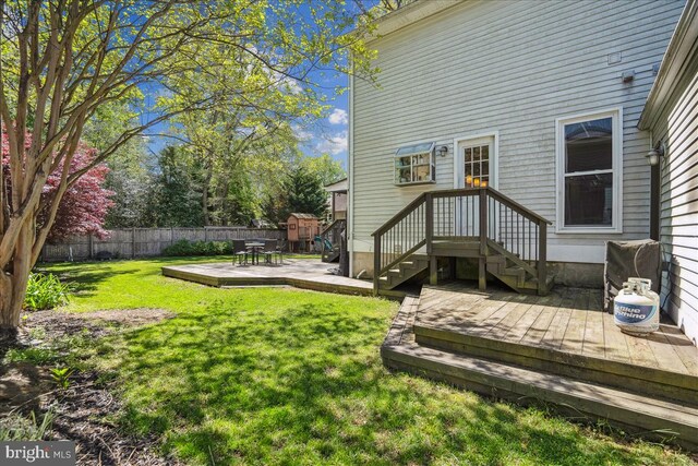 rear view of house with a fenced backyard, a yard, and a deck
