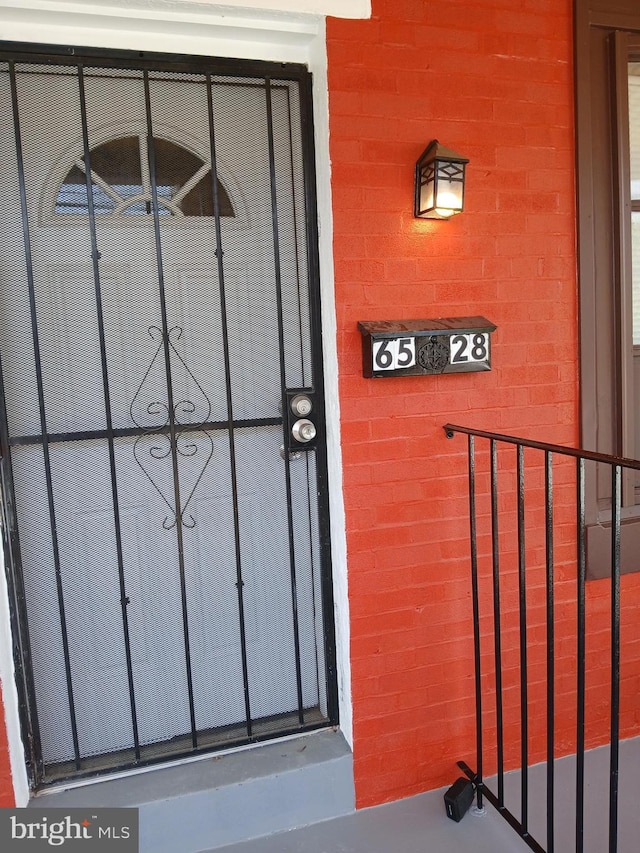 doorway to property with brick siding and a gate