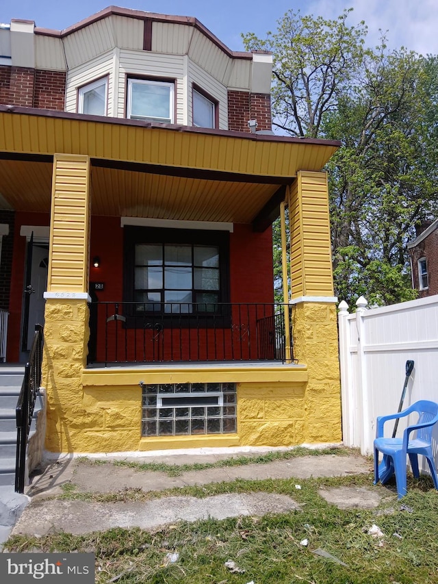 view of home's exterior featuring a porch, fence, and brick siding