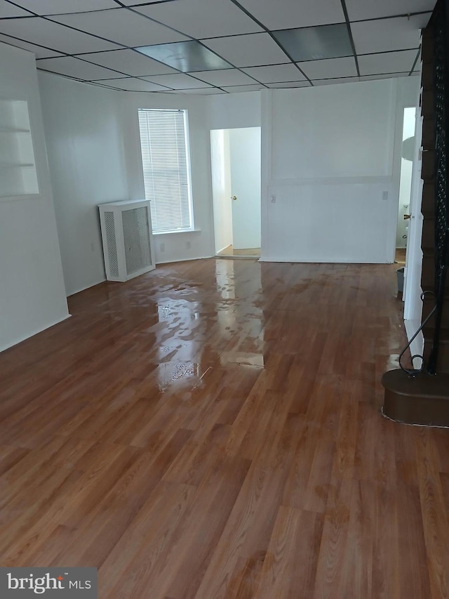 basement with a drop ceiling and wood finished floors