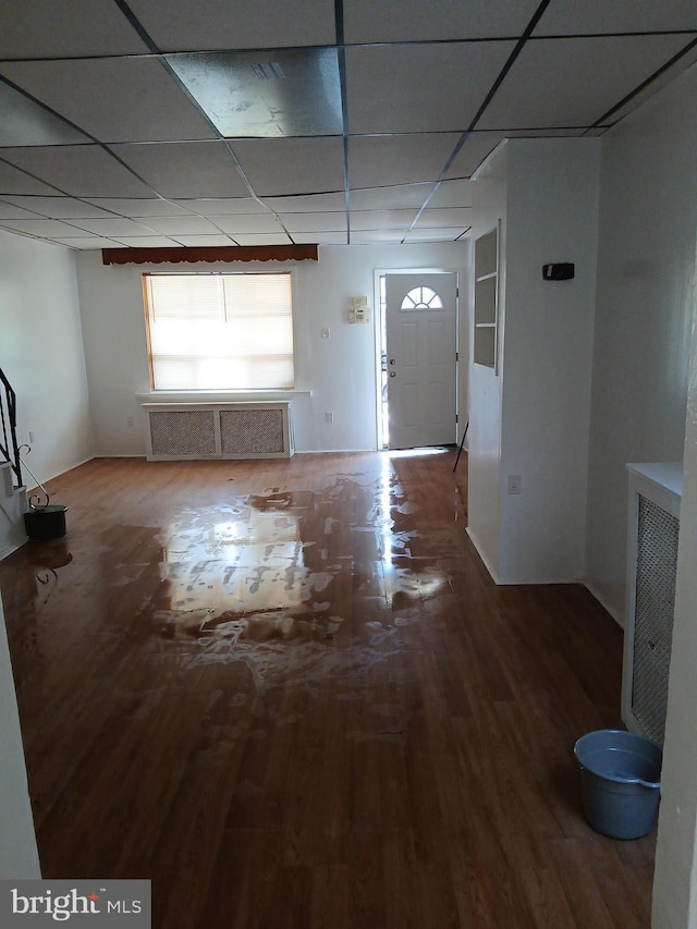 interior space with a drop ceiling and wood finished floors