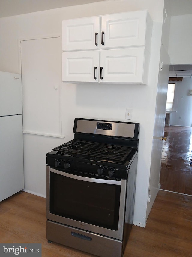 kitchen with wood finished floors, freestanding refrigerator, white cabinetry, and stainless steel gas stove
