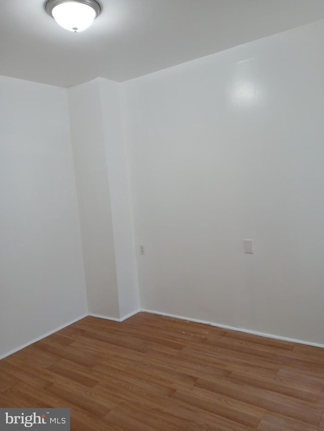 unfurnished room with baseboards and light wood-type flooring