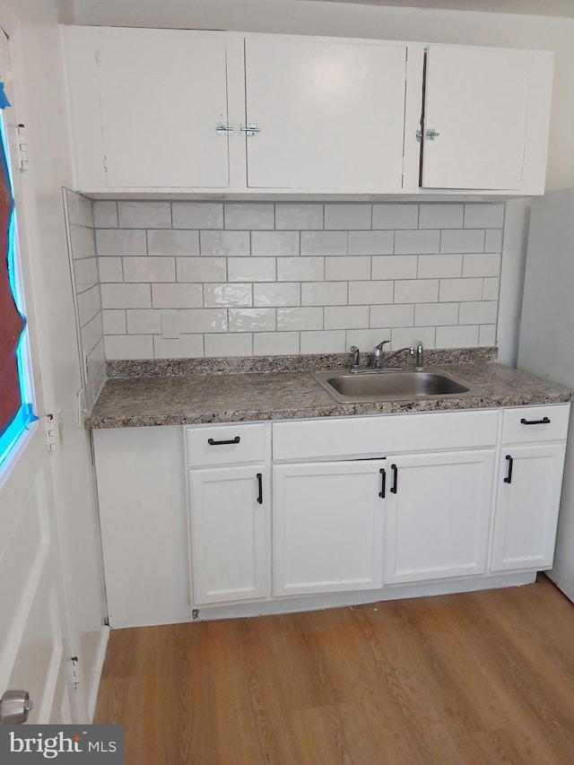 kitchen featuring light wood-type flooring, a sink, and white cabinets