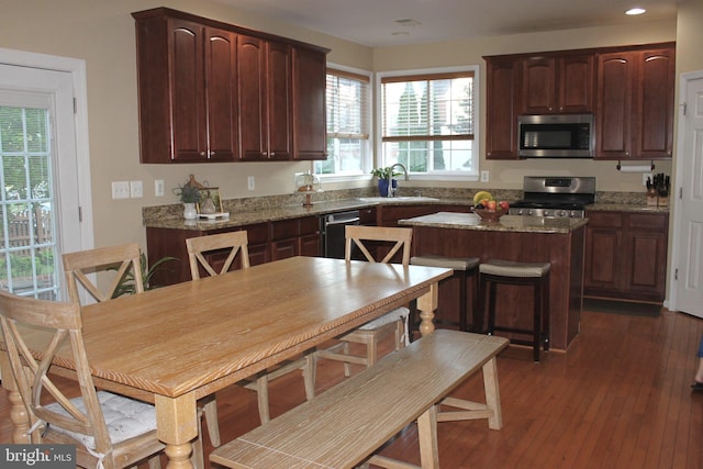 kitchen featuring appliances with stainless steel finishes, a sink, a center island, recessed lighting, and dark wood-style floors