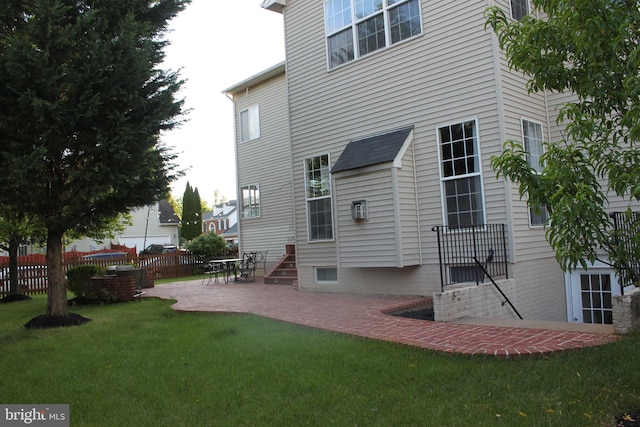rear view of house featuring a lawn, fence, and a patio area