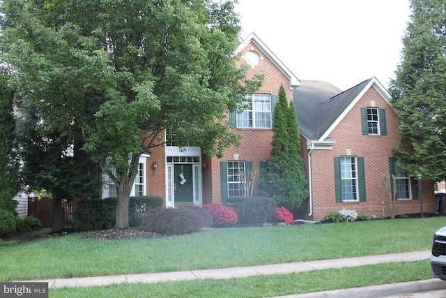 view of front of house with brick siding, fence, and a front lawn