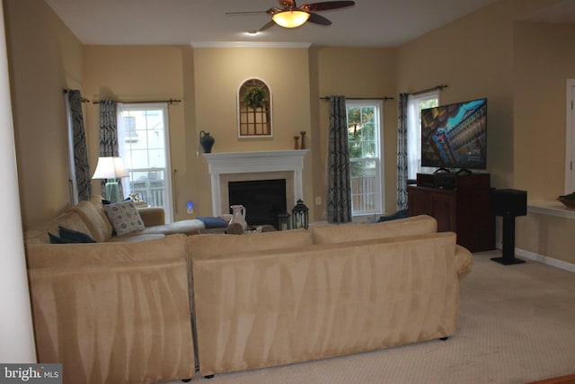 carpeted living room with a ceiling fan, baseboards, a healthy amount of sunlight, and a fireplace