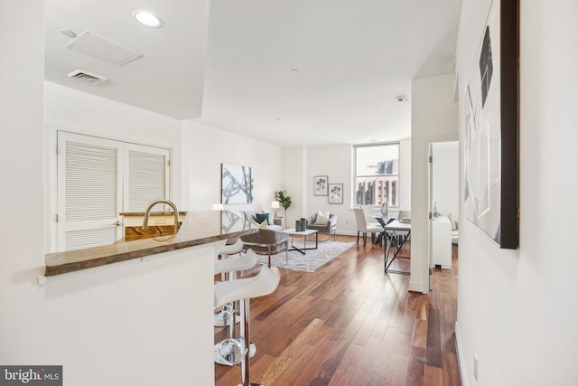 hall with visible vents, a sink, and hardwood / wood-style floors