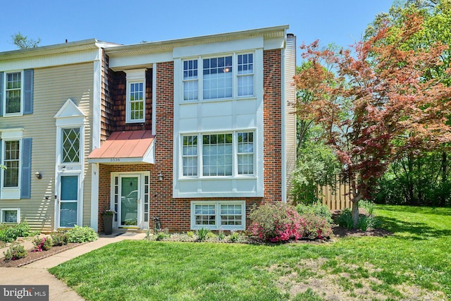townhome / multi-family property with brick siding, a standing seam roof, and a front lawn