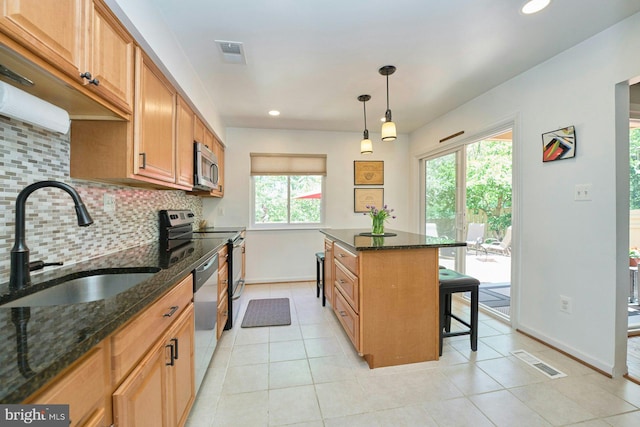 kitchen featuring backsplash, visible vents, appliances with stainless steel finishes, a sink, and a breakfast bar