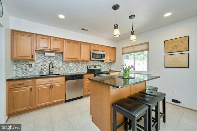 kitchen with visible vents, a kitchen bar, tasteful backsplash, a sink, and stainless steel appliances